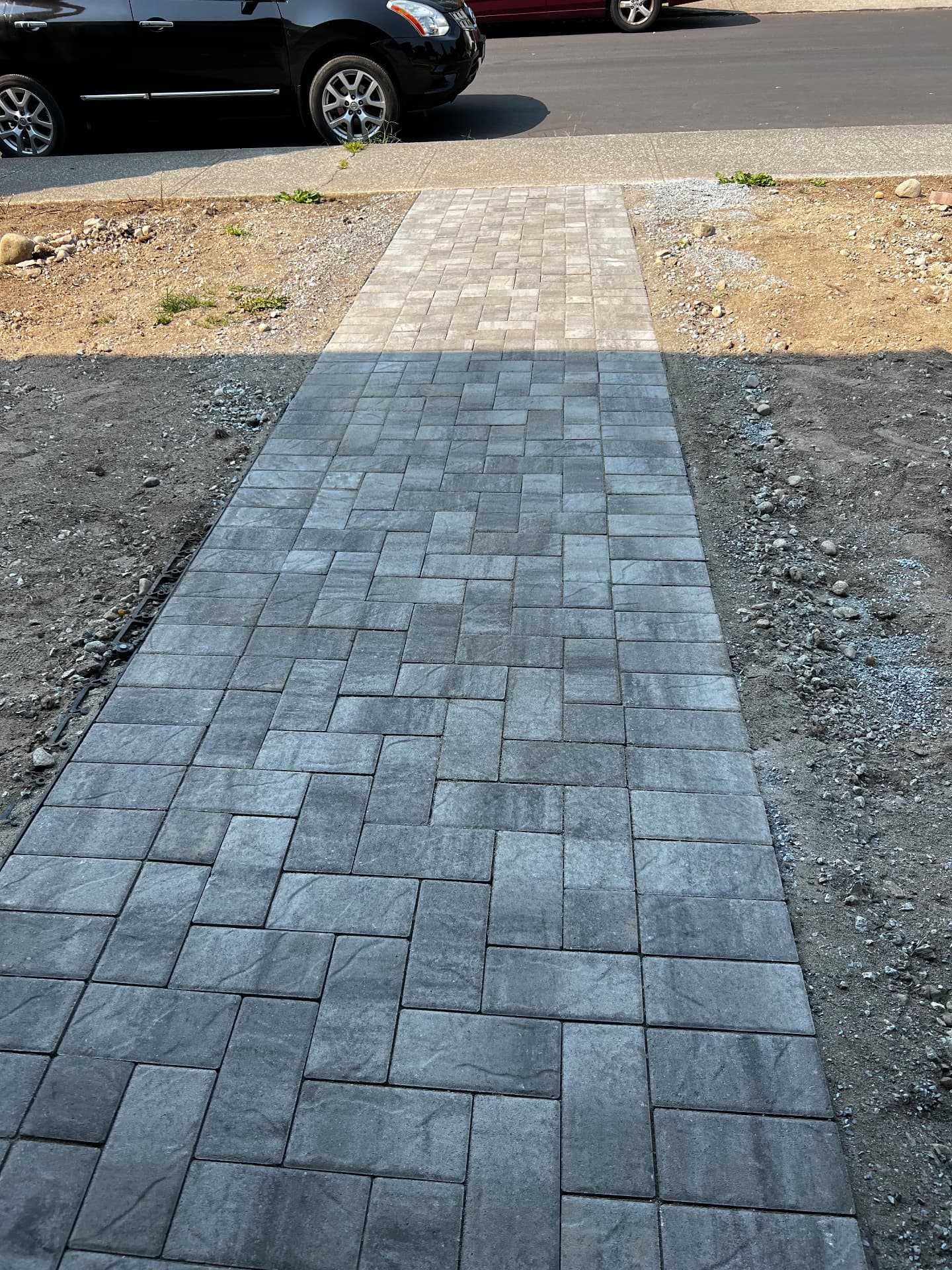 Charcoal and tan paver walkway leading from the sidewalk to a front yard