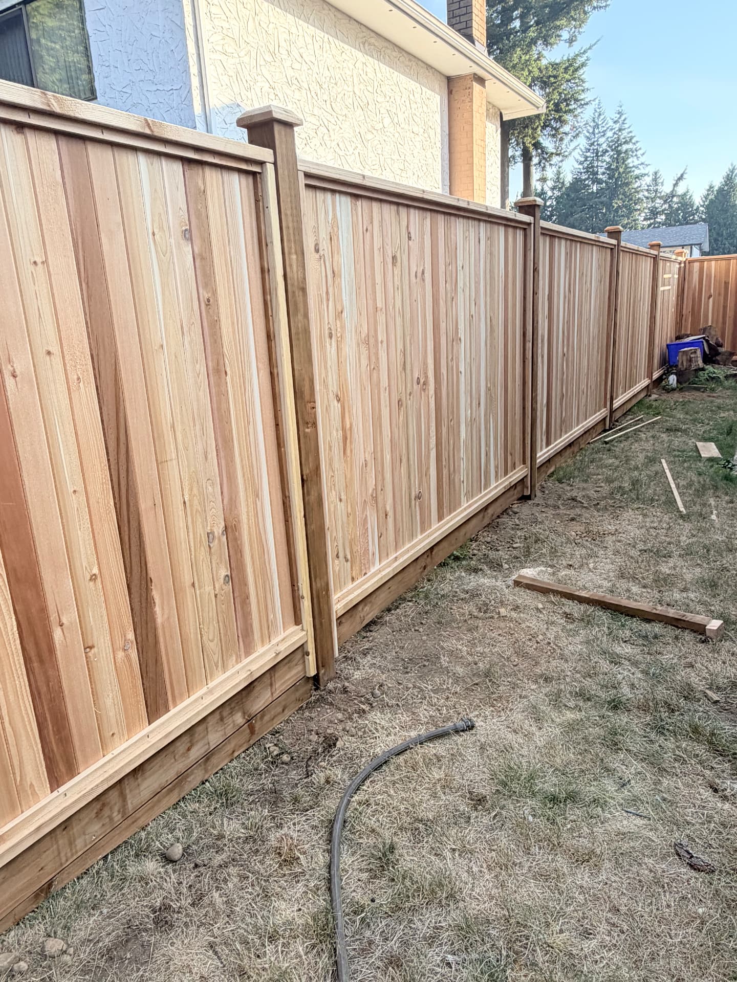 New cedar privacy fence with capped top rail and kickboard running along a side yard