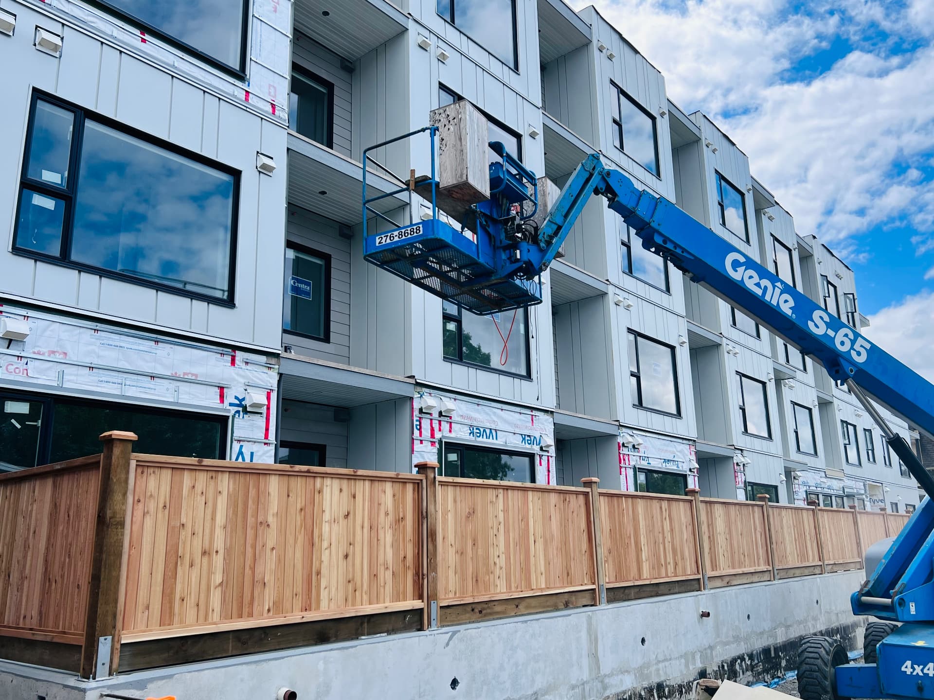 New cedar privacy fence with capped posts running along a townhouse development under construction