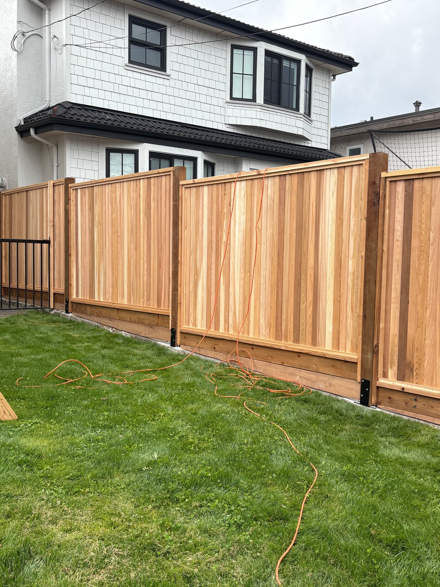 New cedar privacy fence panels installed along a backyard lawn