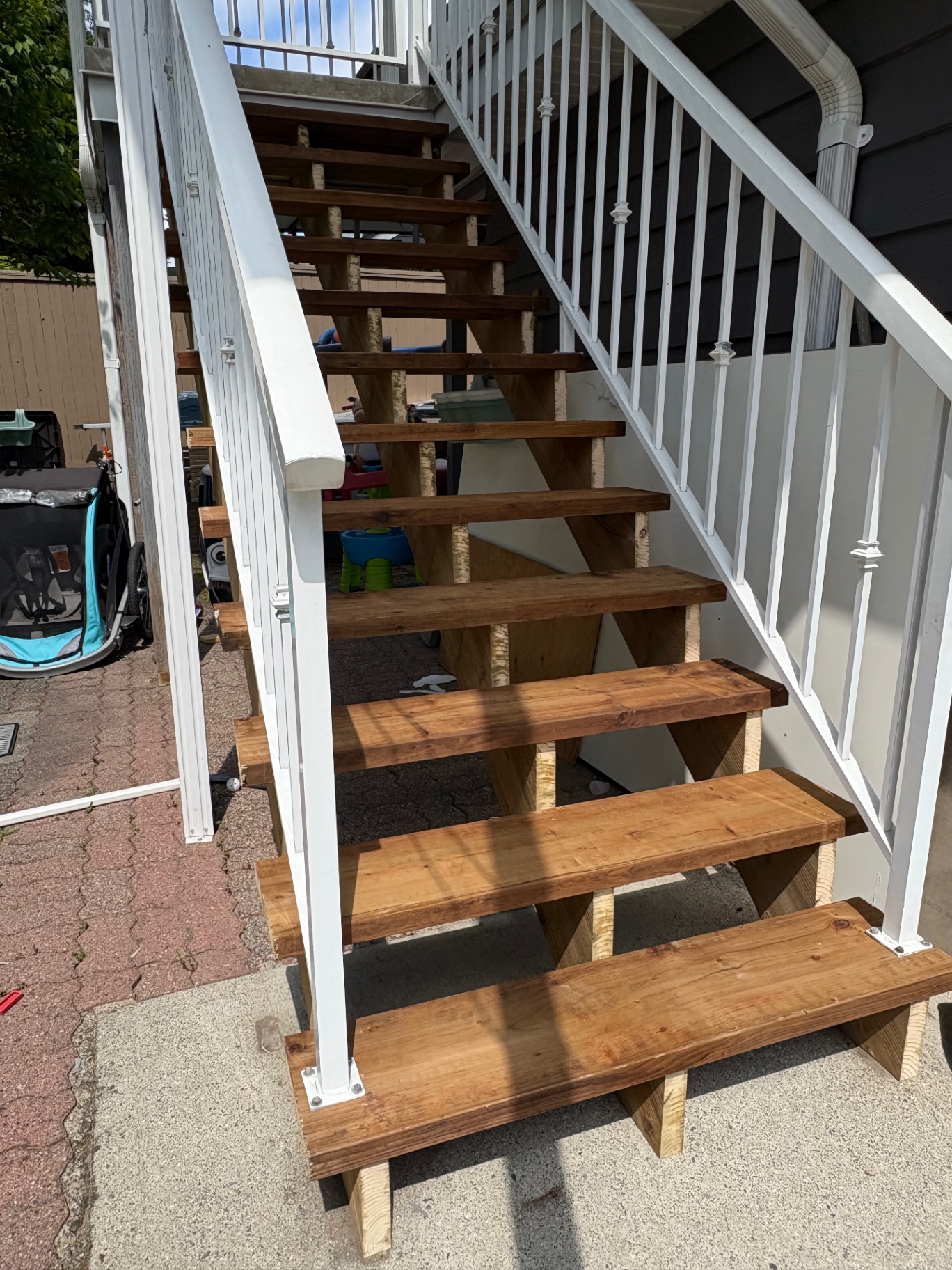 Rebuilt cedar stair treads with white aluminum railing on a two-storey home