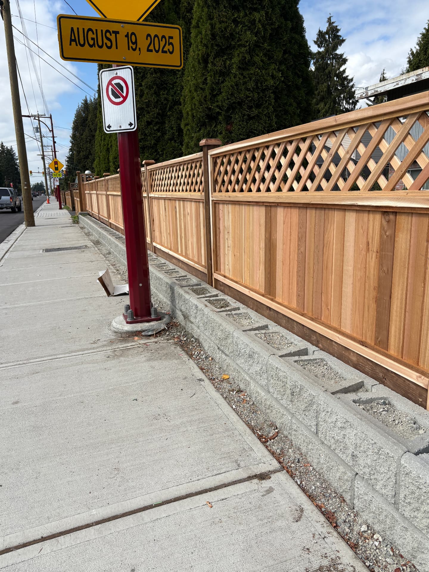 Cedar fence with diagonal lattice top built on a concrete block retaining wall along a sidewalk