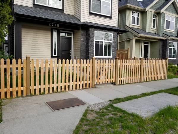 Cedar picket fence along the front yard of a two storey home