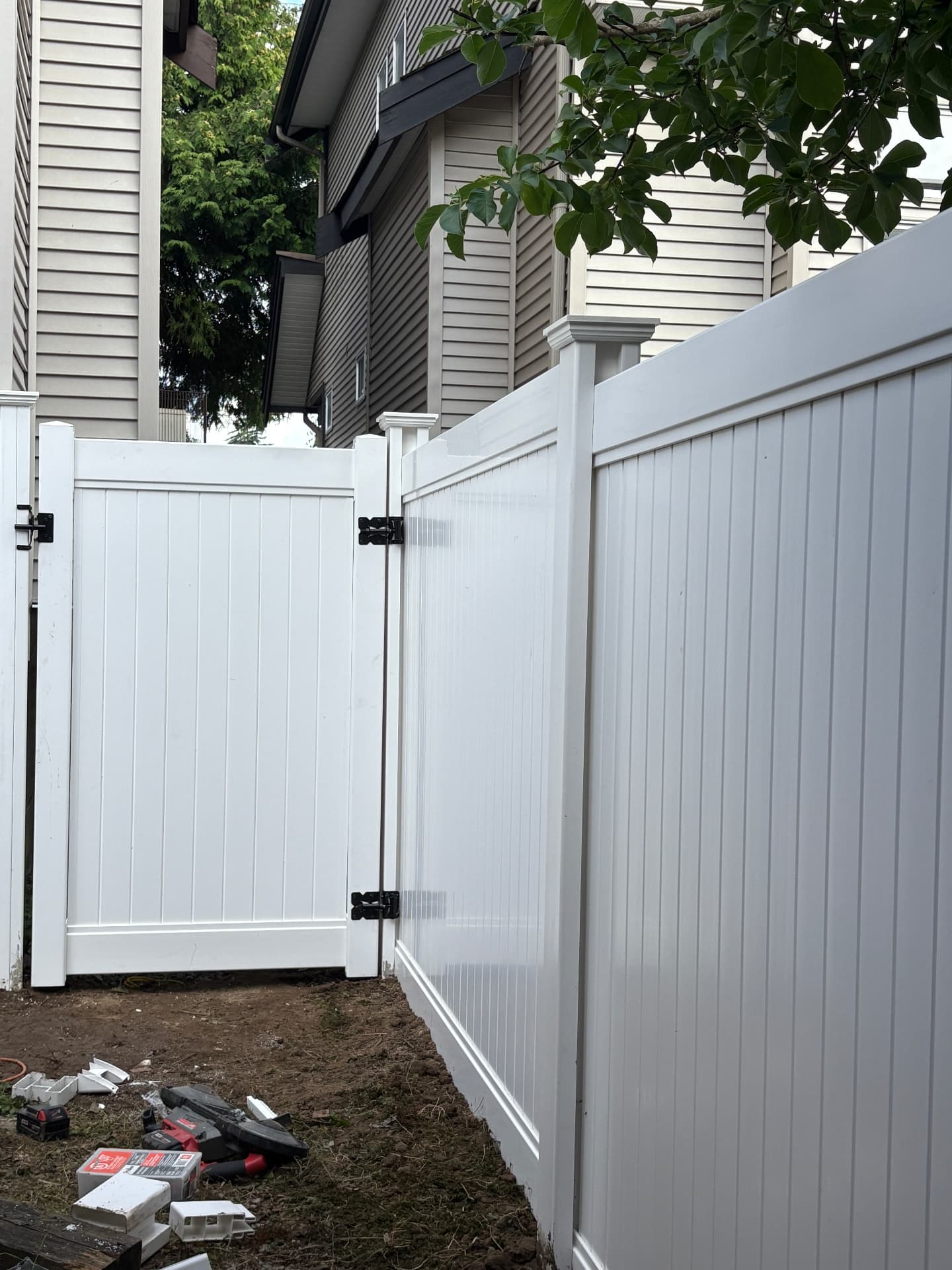 White vinyl privacy fence with a matching double gate between two homes