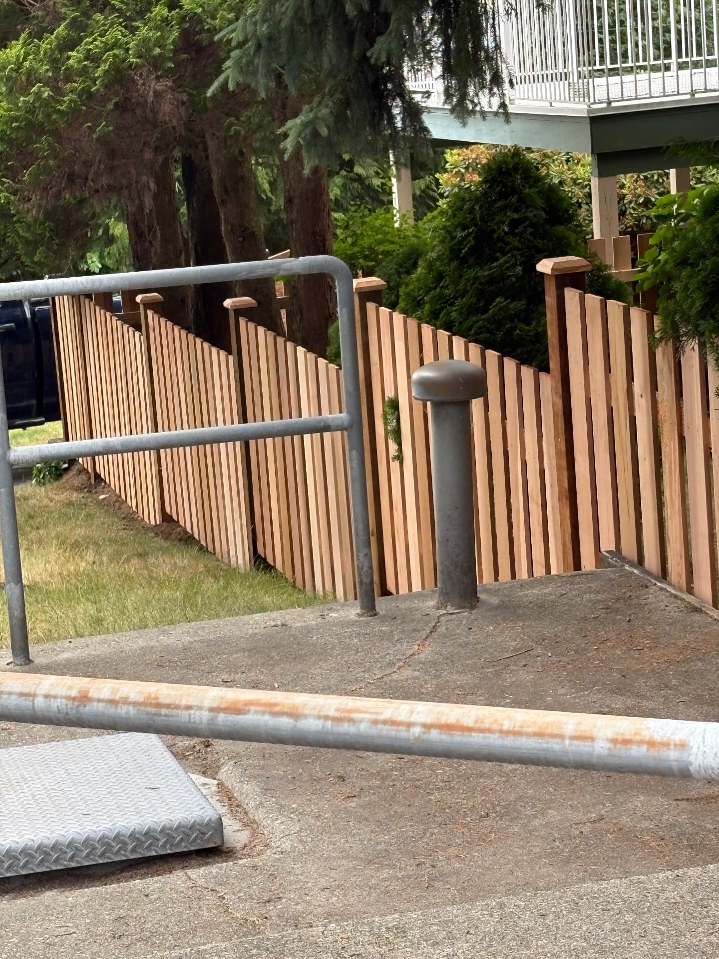 Cedar picket fence stepping down a sloped driveway edge