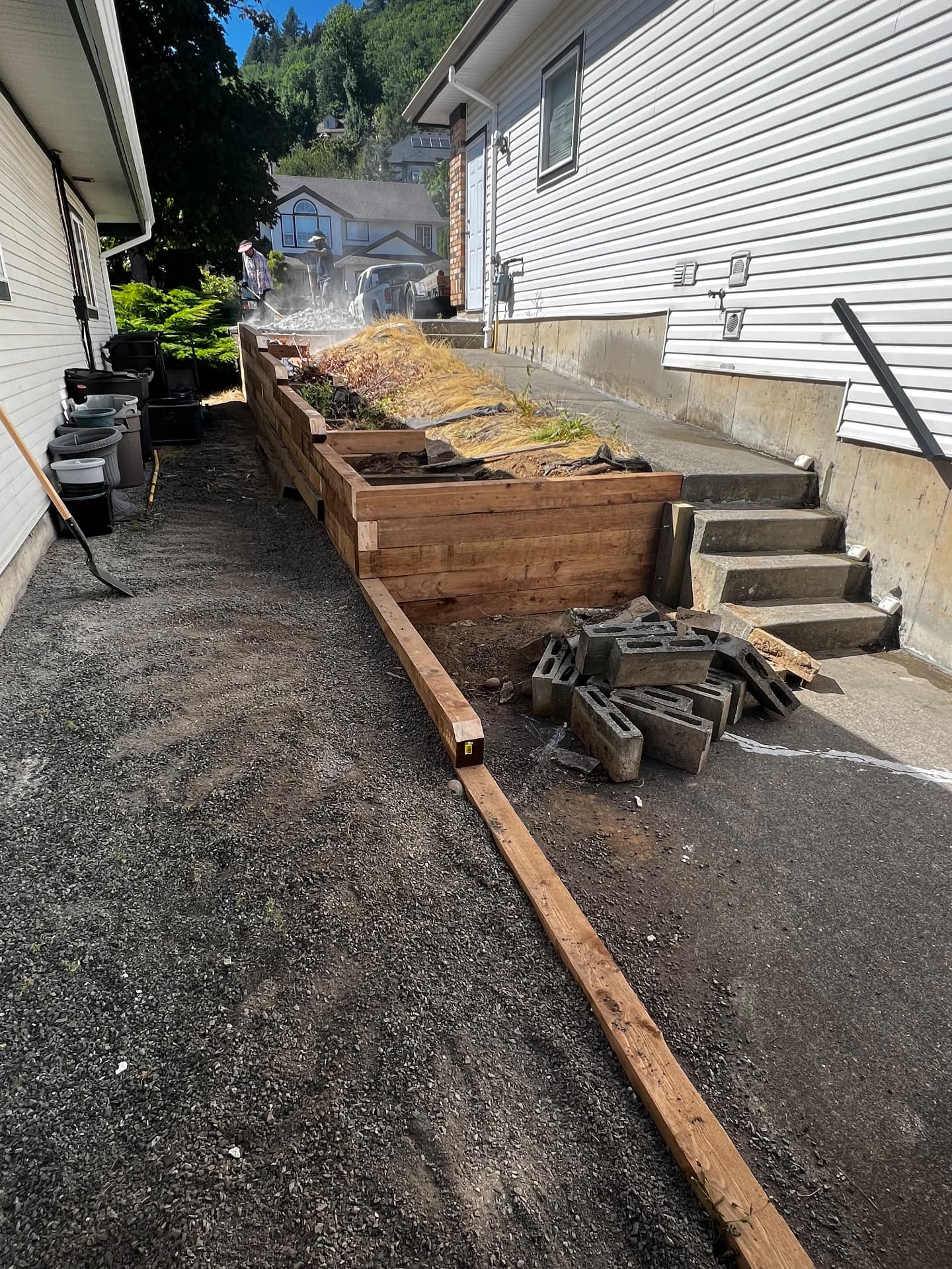 Stacked timber retaining wall and planter terrace running along a narrow side yard