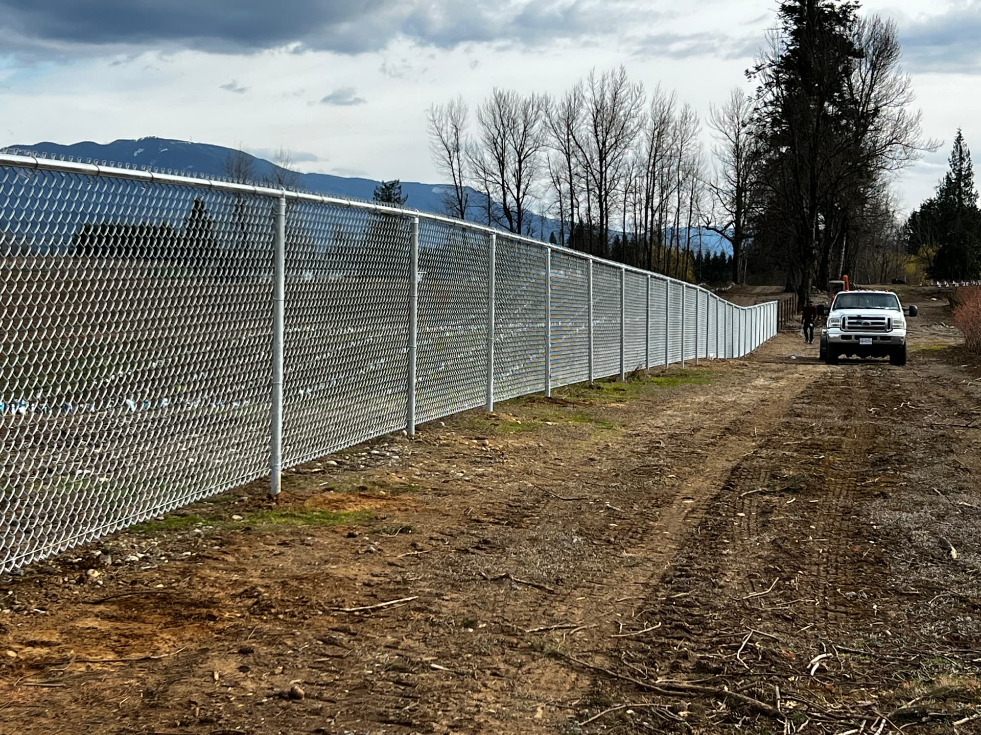 Long galvanized chain link fence with privacy slats securing a commercial acreage