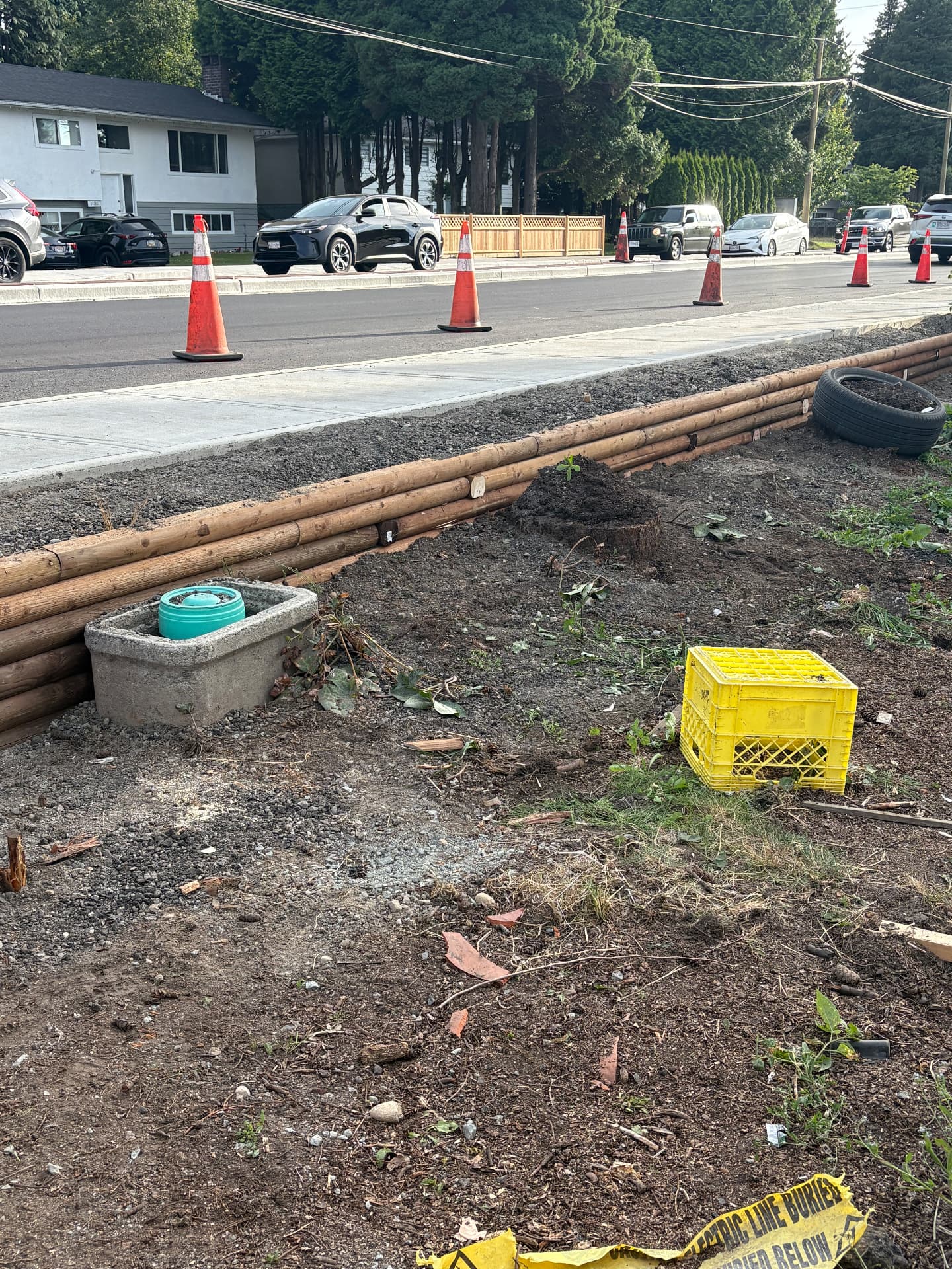 Round timber log retaining wall built along a boulevard beside a new sidewalk