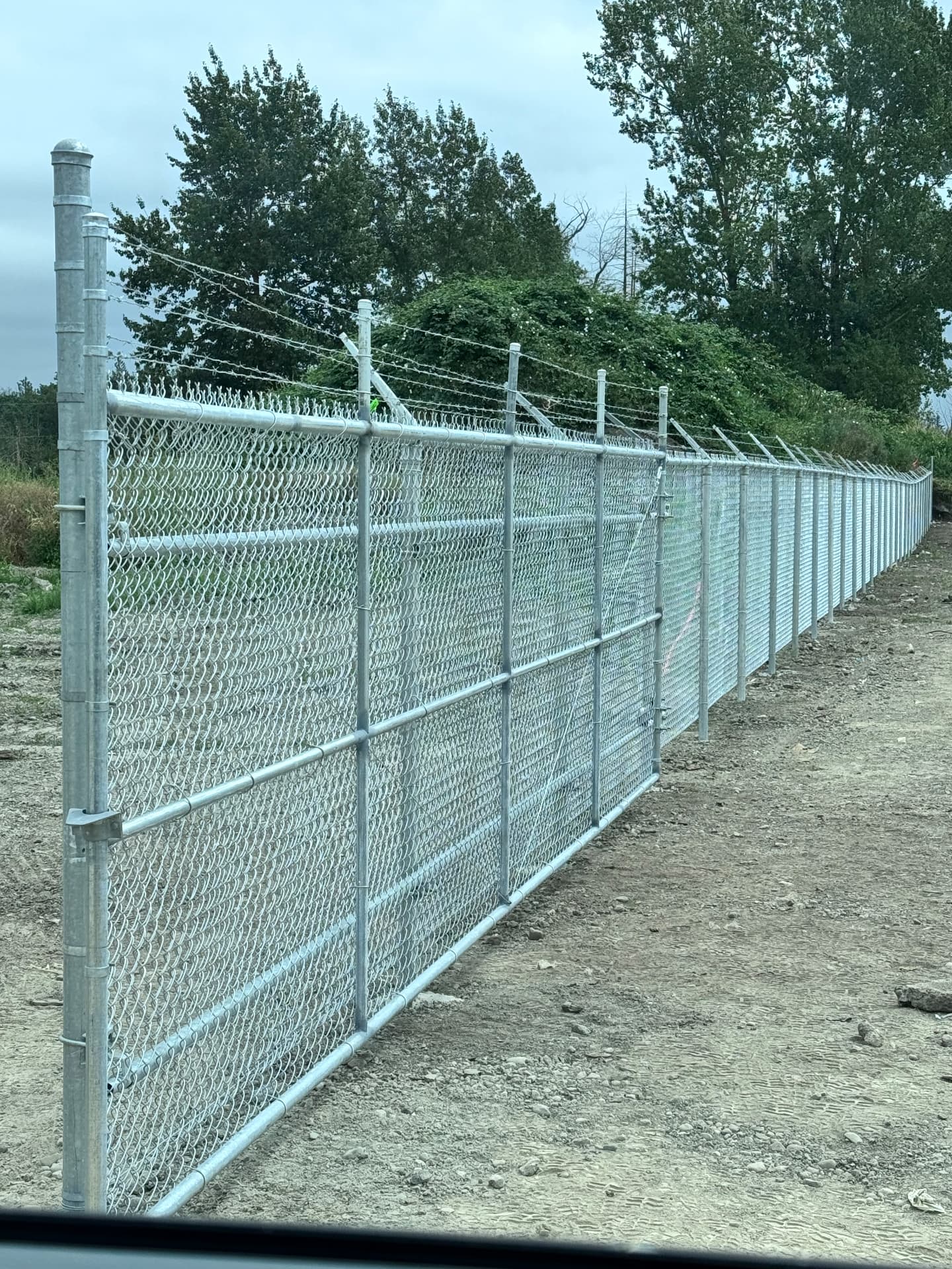 Galvanized chain link security fence topped with barbed wire