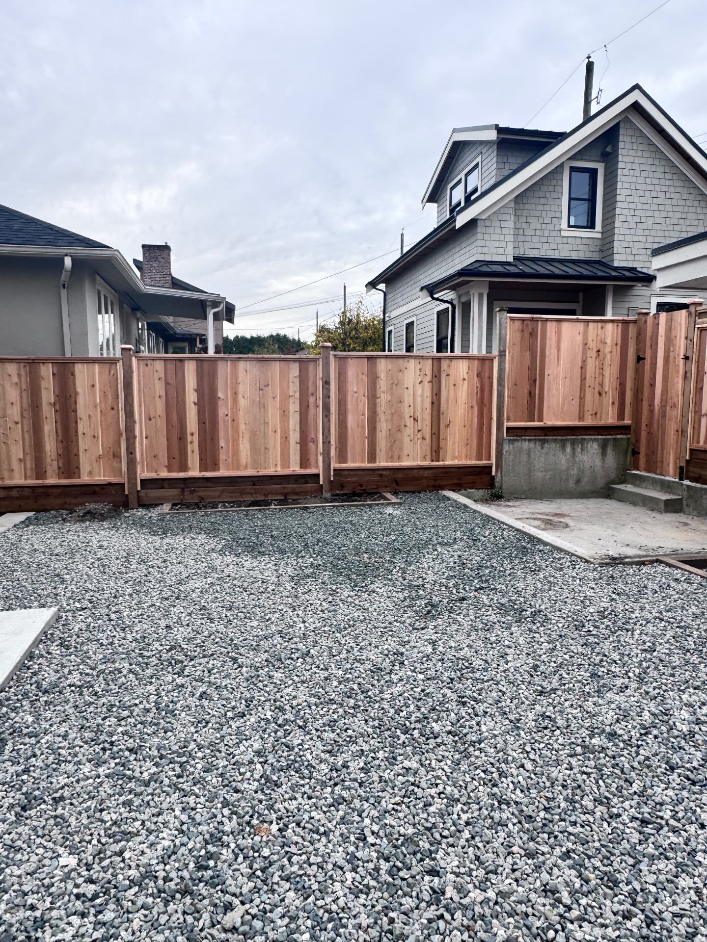 Cedar privacy fence and gate around a new gravel parking pad