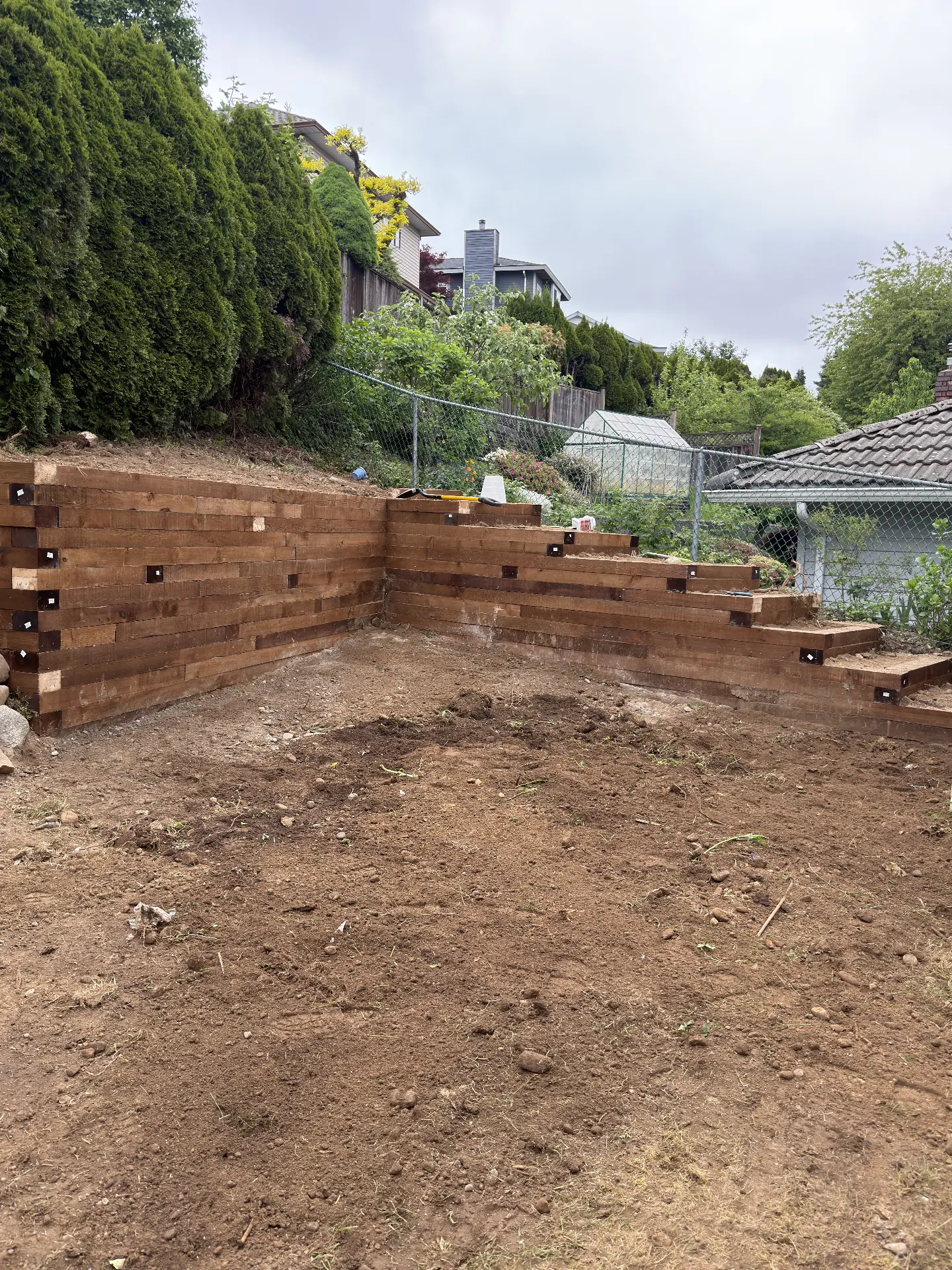 Stained timber retaining wall with stepped terracing at the back of a graded yard