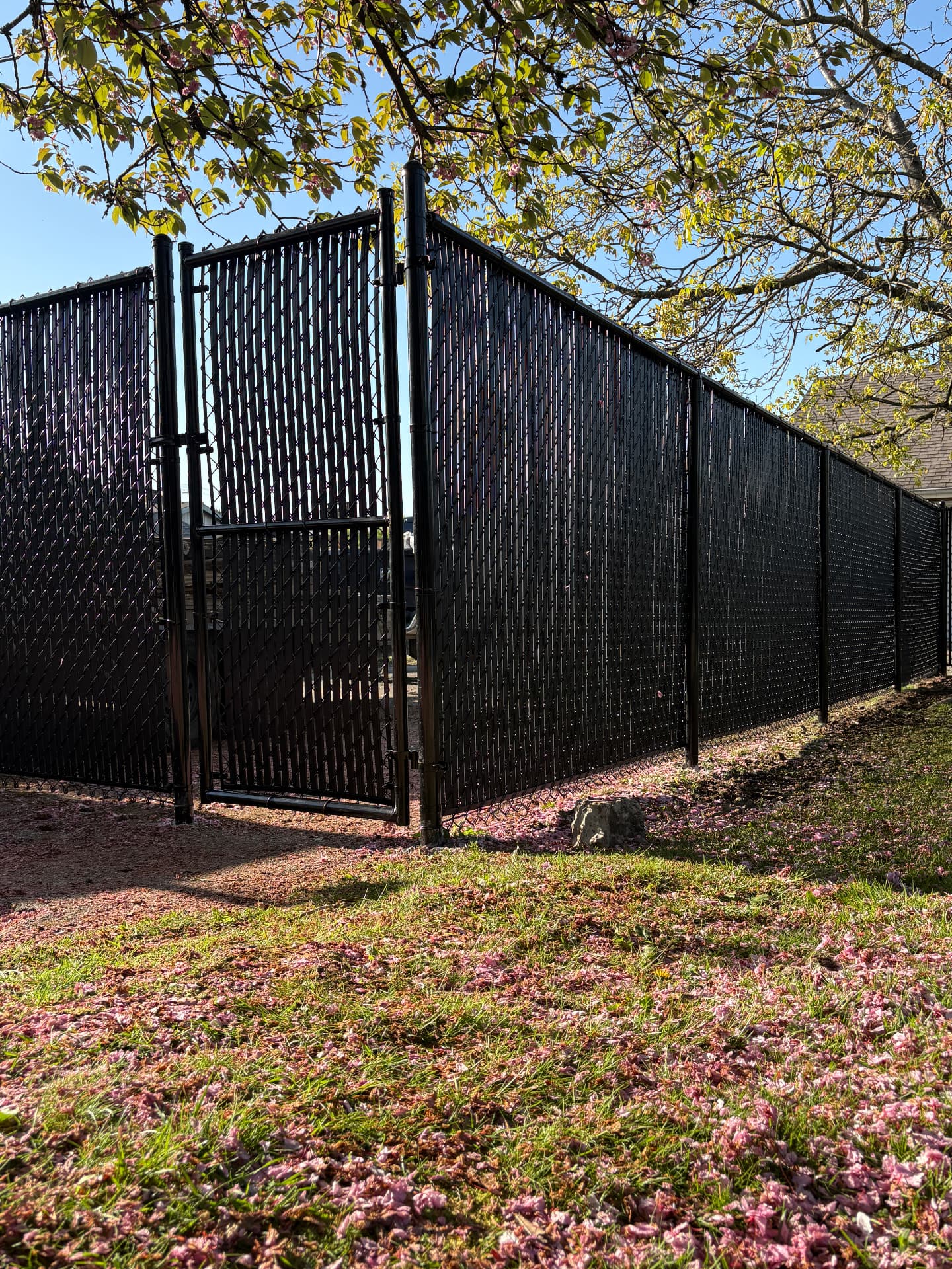 Black chain link fence with privacy slats and a matching walk gate