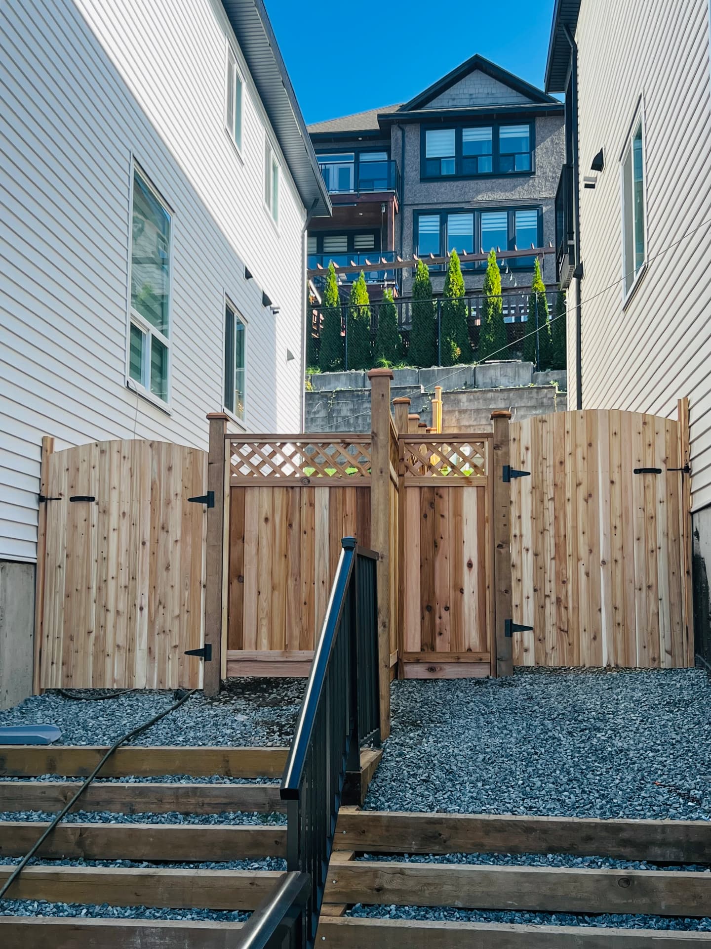 Two arched cedar gates and lattice-top cedar fencing above a timber stair landing